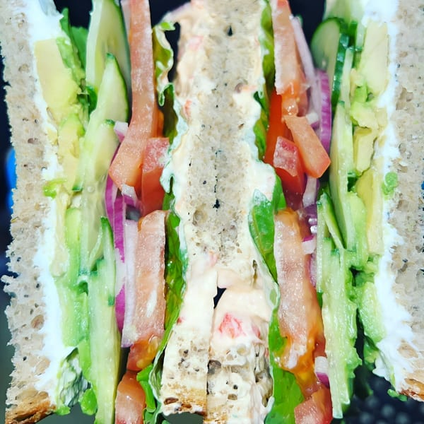 A Domenico's Delicatessen sandwich cut in half, revealing layers of fresh vegetables and creamy filling.